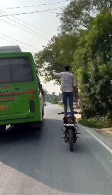 アクロバットなバイク走行でバスに手を振る男