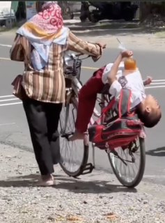 自転車に乗りながら凄い寝方をする少年