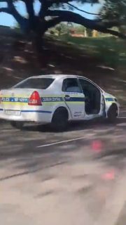事故後に運転席ドアが取れたパトカーで署に戻る警察官