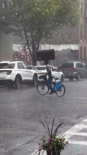 雨の中頭にテレビを乗せながら器用に自転車に乗る人