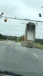 トラックの荷台が上がったまま走行し信号に激突