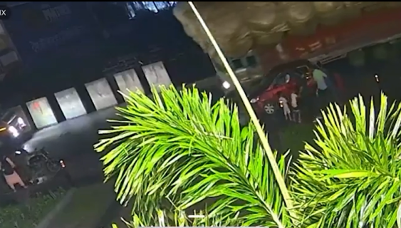 家族の横で大量のわらを積んだトラックが横転