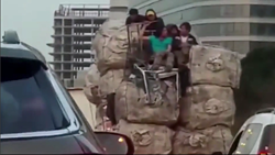 トラックの荷物の山の上に乗る若者たち