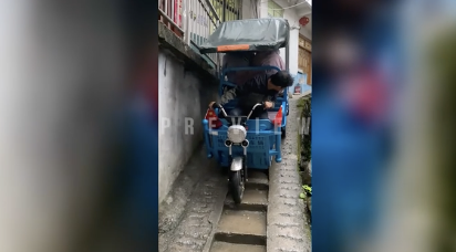 狭い坂道を巧みに操縦する三輪運転手