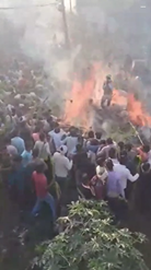 炎の中で立ち尽くす酔っ払いを助ける村人