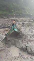 掘削機の上で急な洪水に耐える作業員
